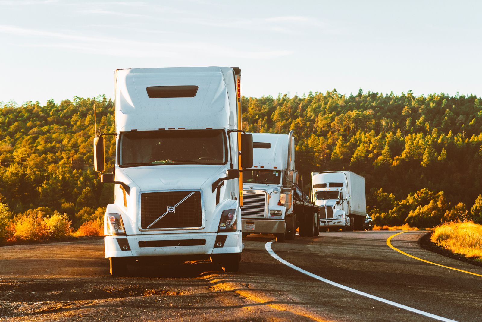 Trucks in convoy on a highway in evening light
